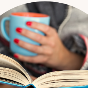 Image: Woman reading a book and holding a cup of coffee